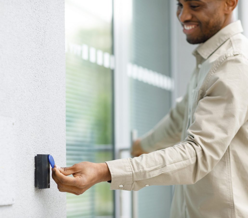 Mitarbeiter nutzt RFID-Transponder an modernem Zutrittsleser für sicheren Zugang zum Gebäude, welches mit Sicherheitstechnik ausgestattet ist.